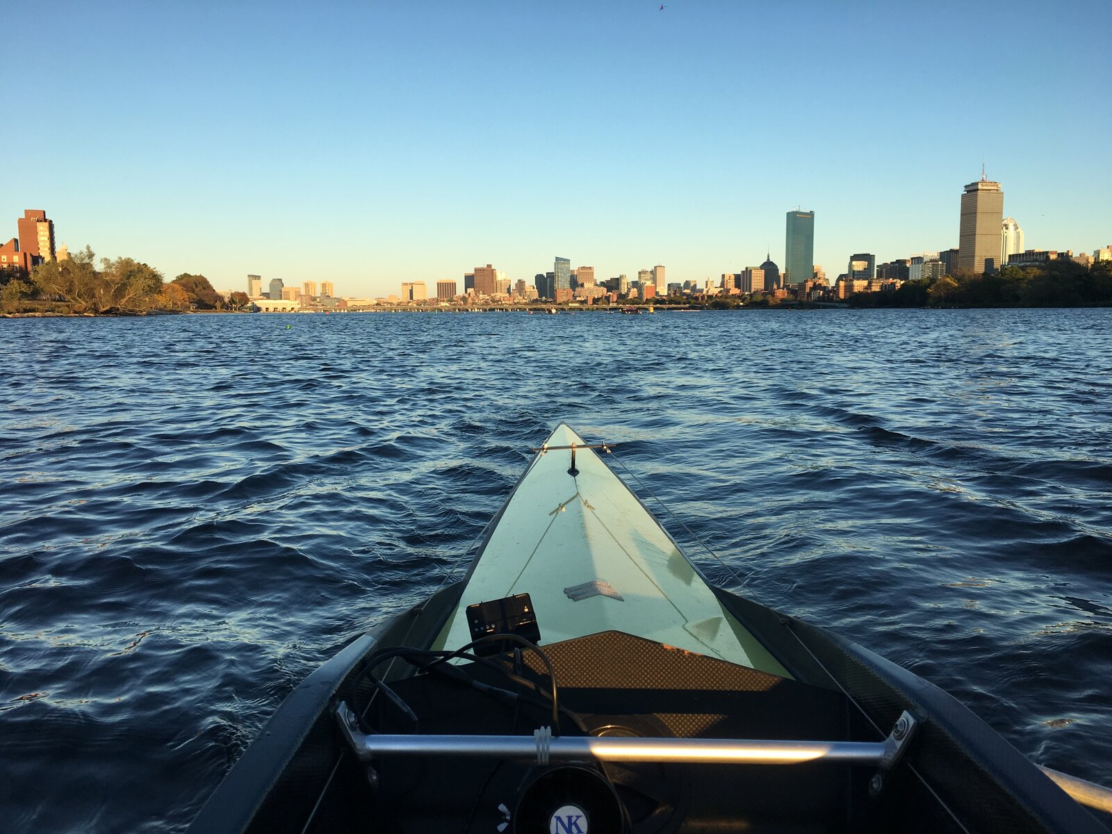 Bow of a single scull on the Charles River with the Boston skyline